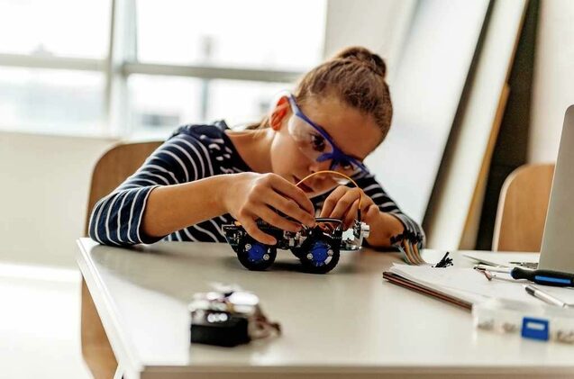 Una niña manipula un pequeño robot.